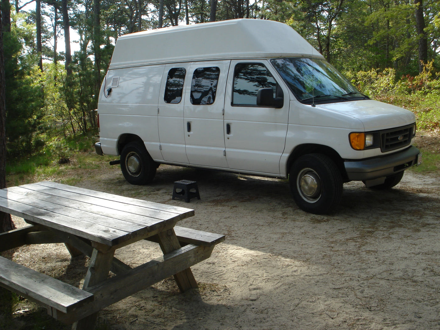  parked on gravel near fall foliage.|White Belaire RV rental parked amongst trees — photo 15