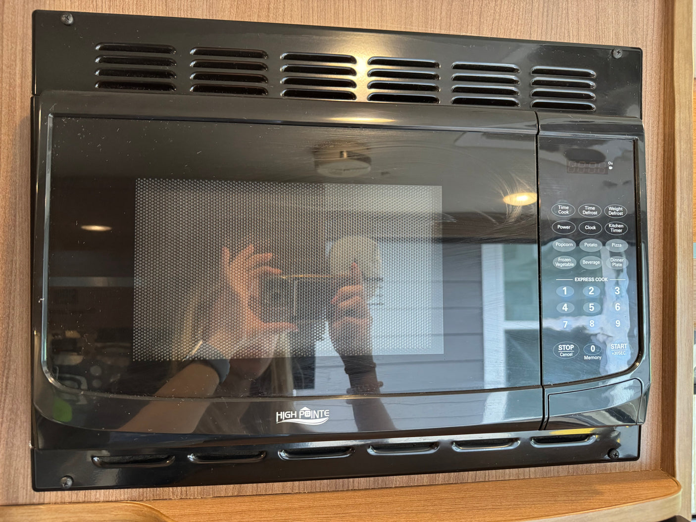 Black High Pointe microwave oven with control panel in an rv rental, reflecting the photographer and exterior view.