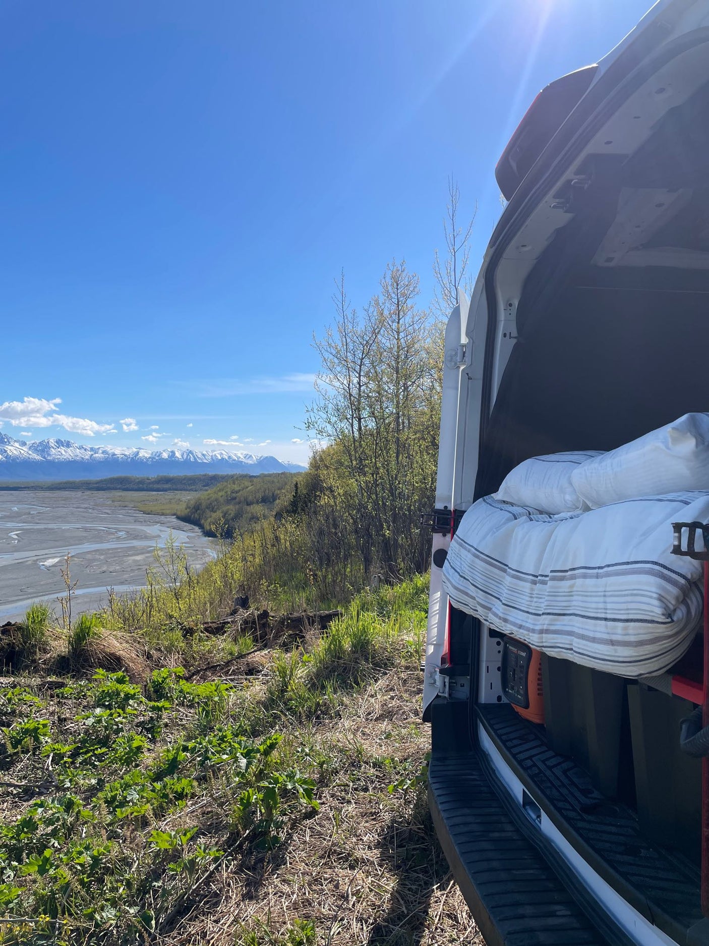 Scenic rv rental view from a camper van overlooking snow-capped mountains & river. Ideal for outdoor adventures & van life.