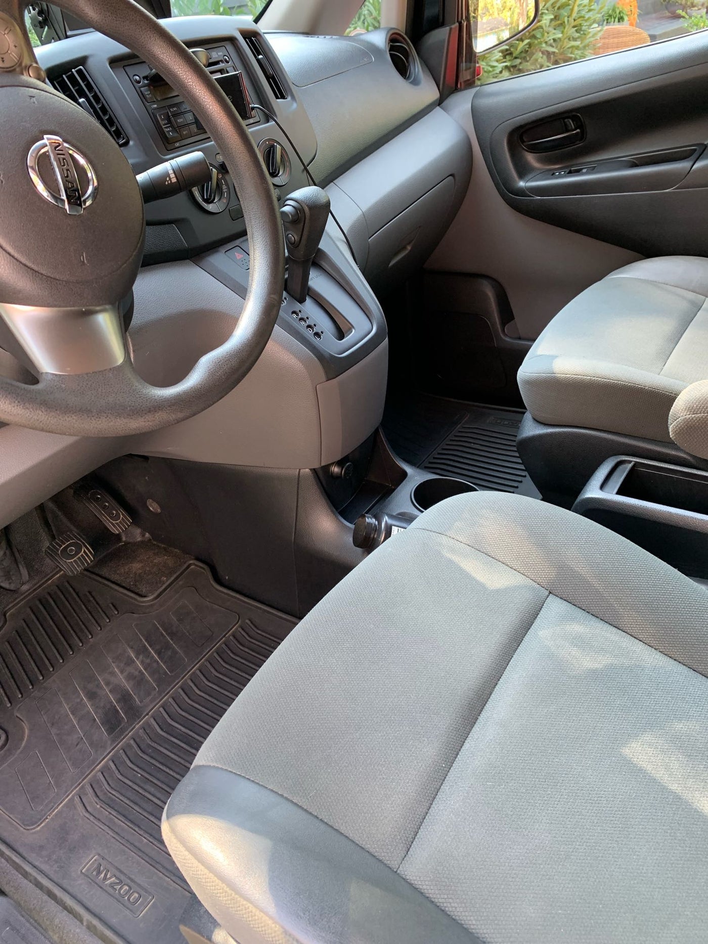 Interior of a Nissan NV200 van, featuring the driver's seat, steering wheel, and dashboard. Perfect for compact RV rental use. — photo 7