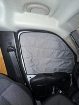 RV rental camper van interior showing a gray, insulated window privacy screen, a seatbelt, and car ceiling.