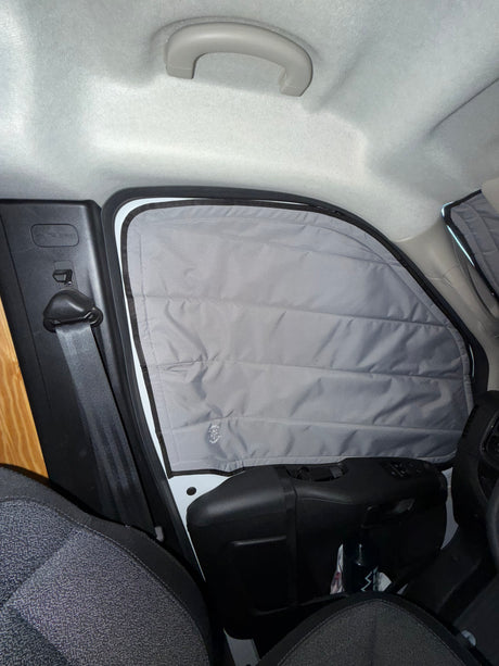 RV rental camper van interior showing a gray, insulated window privacy screen, a seatbelt, and car ceiling.