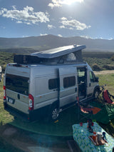 Winnebago Solis rv rental setup for camping, featuring an open pop-top & outdoor gear against a scenic mountain backdrop.