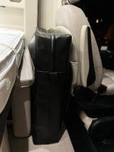 RV rental interior: A cozy bed with white mattress, a black standing luggage bag, and a light-colored passenger seat, ready for adventures.