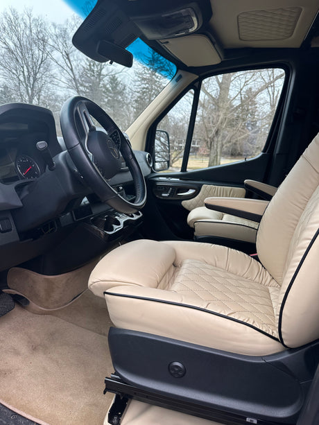 Luxury RV rental interior with cream quilted leather seats. View of dashboard and steering wheel.