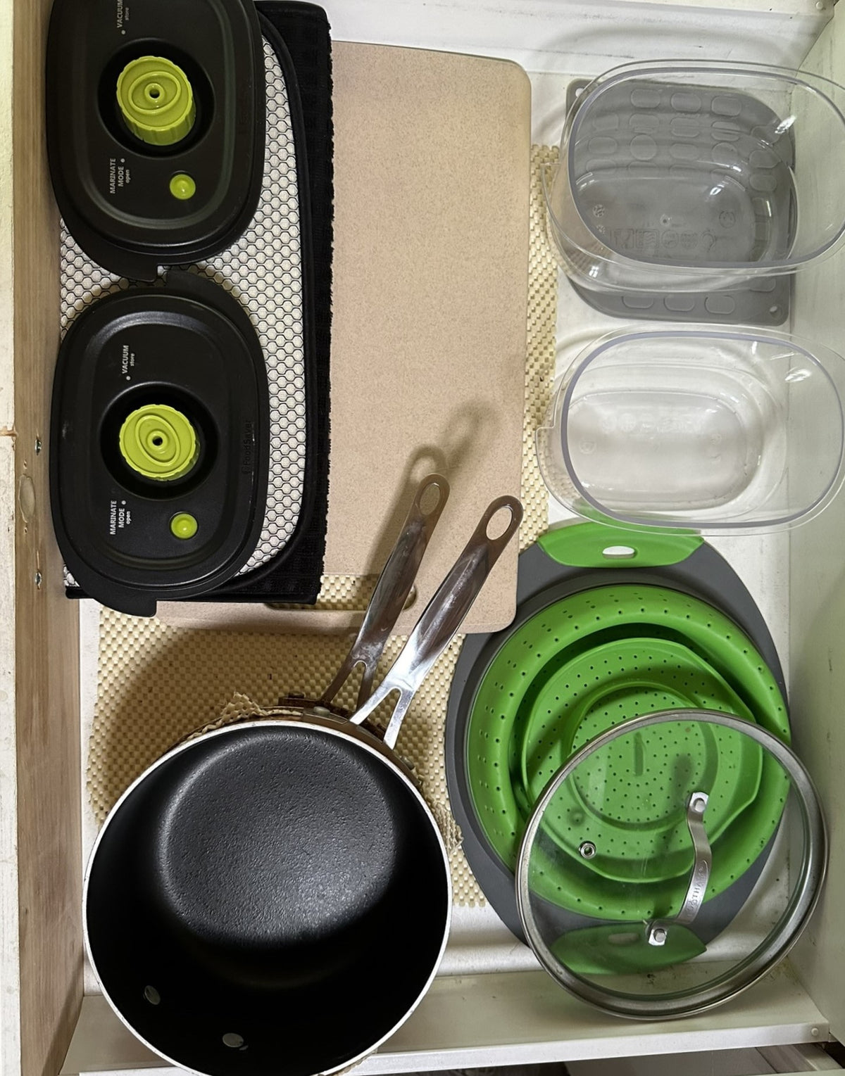 Compact RV rental kitchen storage: vacuum sealers, collapsible colander, saucepan, and food containers neatly organized. — photo 13