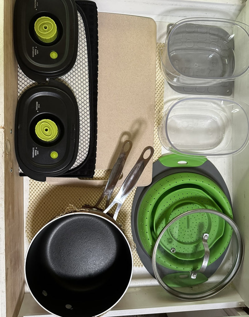 Compact RV rental kitchen storage: vacuum sealers, collapsible colander, saucepan, and food containers neatly organized. — photo 13