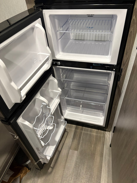 Open, clean, and empty RV rental refrigerator with a top freezer, ready for provisions.