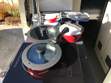 RV rental kitchen setup: portable induction cooktop, pots, collapsible bowls, and utensils for compact travel cooking.