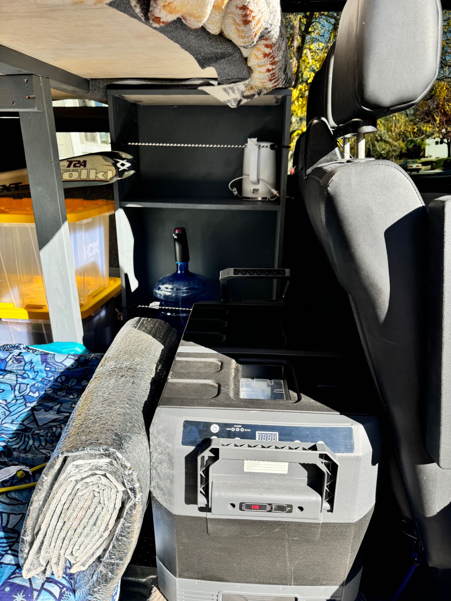 Compact rv rental interior featuring a portable fridge, water, and smart storage solutions for adventurous road trips.