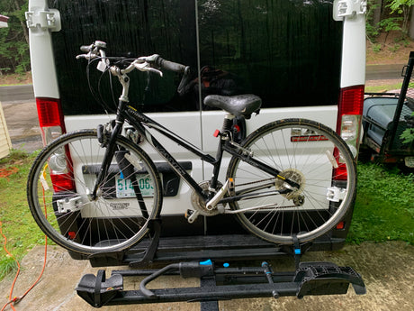 A Jamis Citizen bike on a rear rack of a white rv rental van, hinting at road trips & nature exploration.