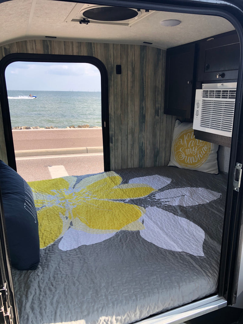 Cozy RV rental interior with a comfortable bed, AC unit, and a scenic waterfront view with a jet ski. — photo 3