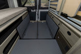 RV rental camper interior: versatile bed, open storage bins, and hinged floor panels for extensive cargo capacity.