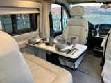 Spacious rv rental interior featuring a practical dining table with place settings, ideal for comfortable meals on your road trip.