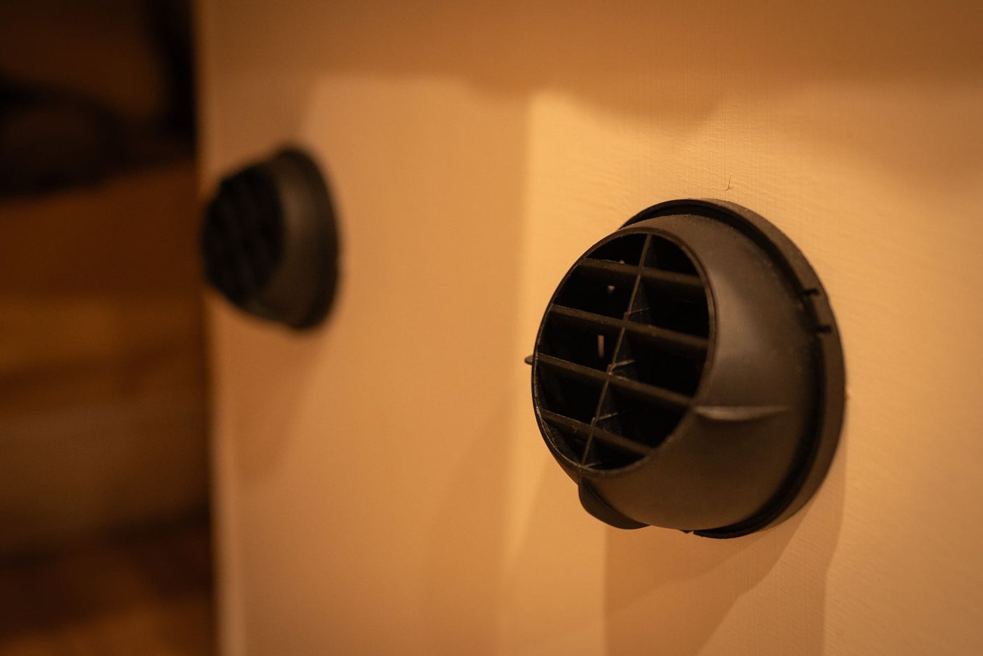 Keep cool in your RV rental! Focus on two black circular air vents on a light-colored interior wall, part of the climate system.