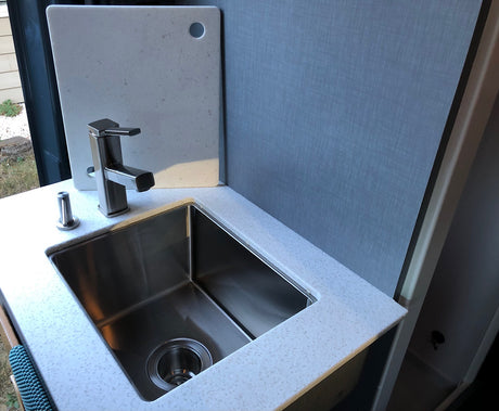 Modern kitchen in an RV rental with a stainless steel sink, sleek faucet, and white speckled countertop. Compact and functional.
