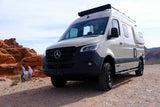 Winnebago Mercedes-Benz Sprinter RV rental on a dirt road in a red rock desert. People walk nearby, enjoying the views.