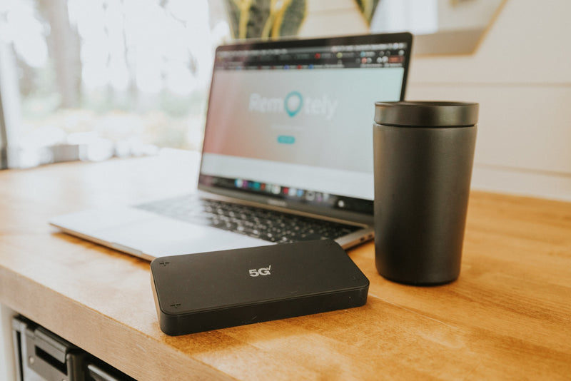 rv rental mobile office setup: A 5G device, laptop showing 'Remotely,' and mug on a wooden desk. — photo 10