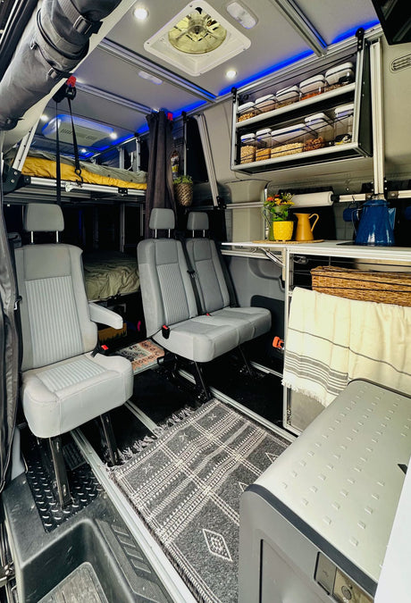Inside this modern RV rental, find versatile seating, an elevated bed, and clever storage, perfect for comfortable mobile living.