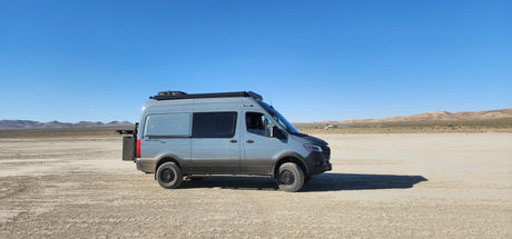 Grey Revel camper van on a dry lakebed, perfect for your next rv rental adventure. Explore the desert!