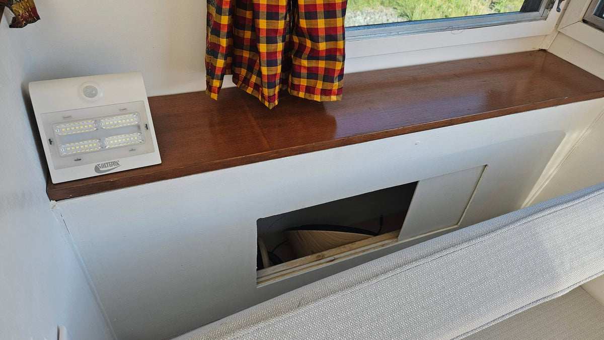 Smart storage solutions in an RV rental: a built-in bench with a hidden compartment, Valterra LED light, and window. — photo 11