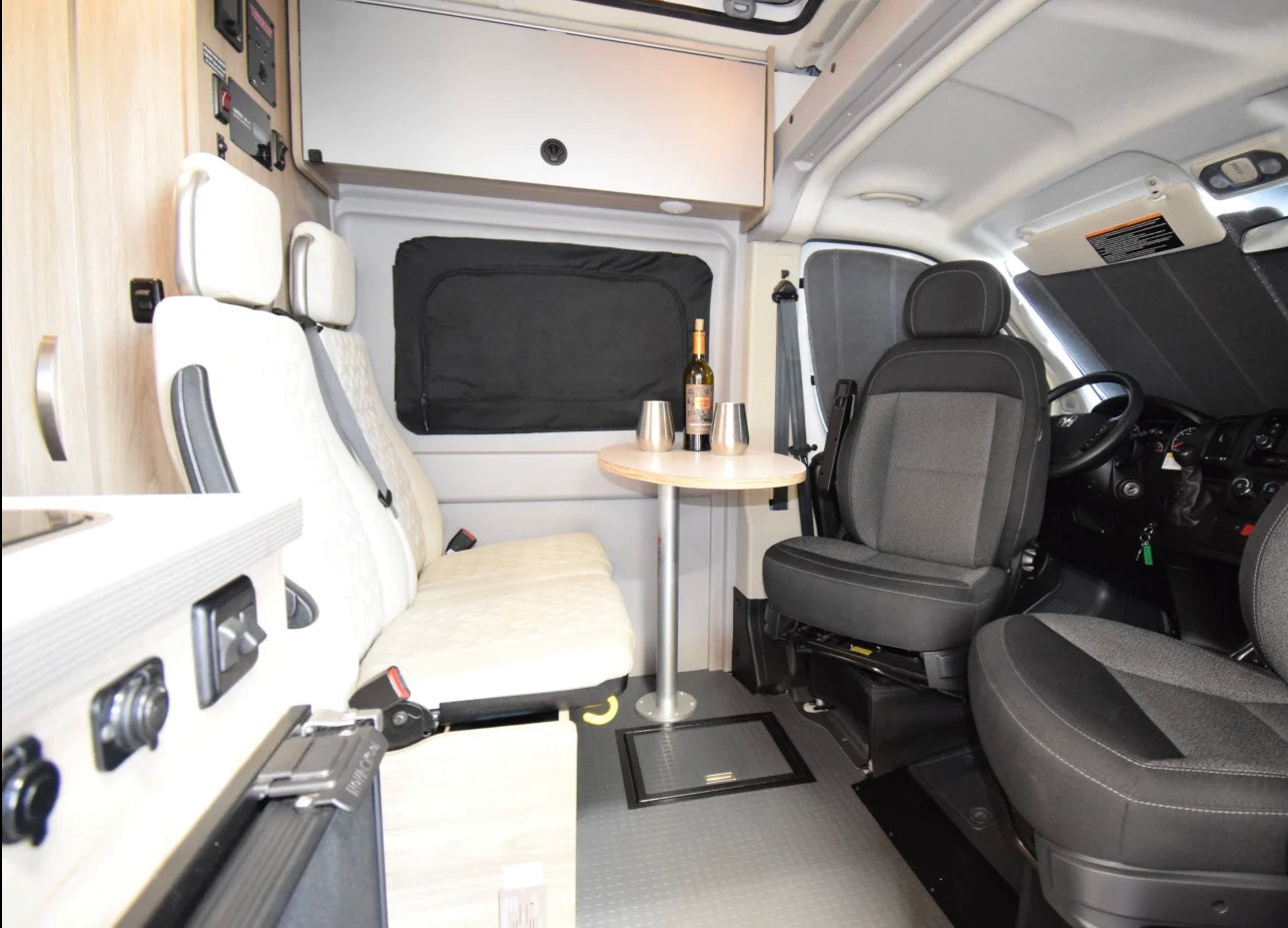 Spacious RV rental interior featuring a dinette table, comfortable seating, and kitchenette. Swivel driver seats visible.