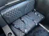 Luxurious black quilted leather seating with safety belts and wood-grain console, ideal for your RV rental comfort.
