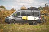 Adventure-ready grey RV rental van, fully equipped with surfboard, bikes, and a roof box for your next outdoor journey.