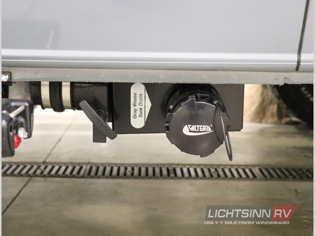 RV rental underside: Valterra gray waste tank drain, valve, and cap for waste disposal.