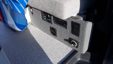 RV rental interior showing power panel, gas detector, AC outlet, and battery switch on a carpeted floor.