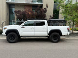 A white Toyota Tacoma TRD Pro pickup truck with a rooftop tent, an overlanding rig ready for adventure, like an RV rental.