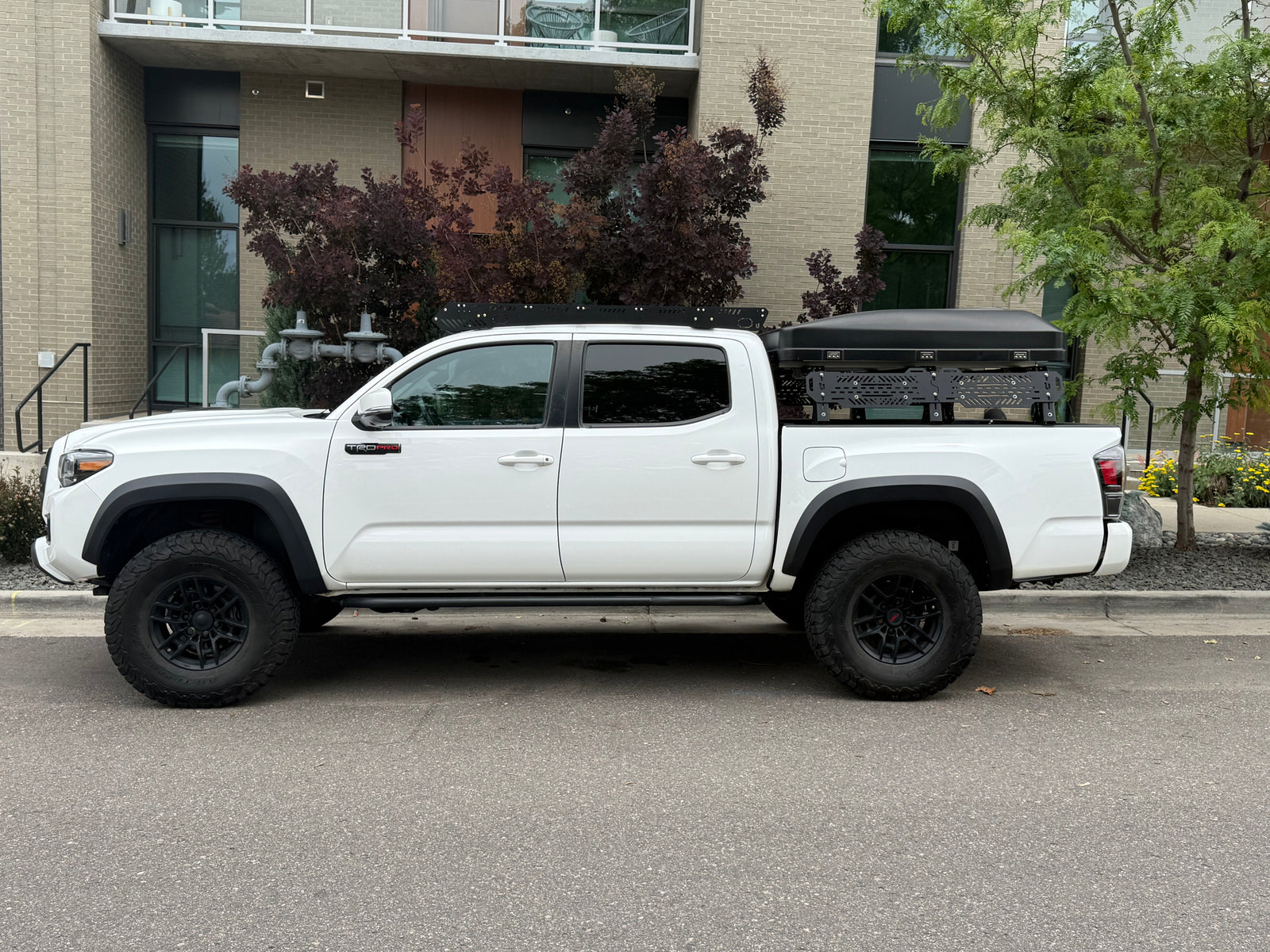 A white Toyota Tacoma TRD Pro pickup truck with a rooftop tent, an overlanding rig ready for adventure, like an RV rental.