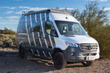Silver Mercedes Sprinter rv rental camper van with a unique camo wrap on a desert dirt road. Adventure awaits!