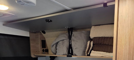 RV rental overhead cabinet reveals organized blankets, towels, and power outlets, offering convenient storage.