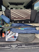 Packed RV rental interior: camping bags, hoses, and a spare tire stored efficiently under the rear seat for adventures.