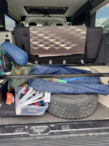 Packed RV rental interior: camping bags, hoses, and a spare tire stored efficiently under the rear seat for adventures.