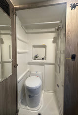RV rental wet bath interior: compact shower/toilet combo in white molded plastic.
