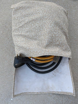 Beige fabric bag holding an RV rental power adapter & electrical cables on concrete, essential for your trip.