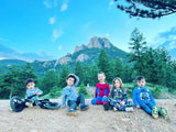 Five children posed on a dirt path with mountains & trees in the background. An RV rental trip would be perfect for this family outdoor fun!