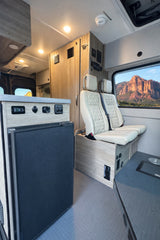 Modern **rv rental** interior with comfy seating, fridge, and a breathtaking desert mountain view from the window.