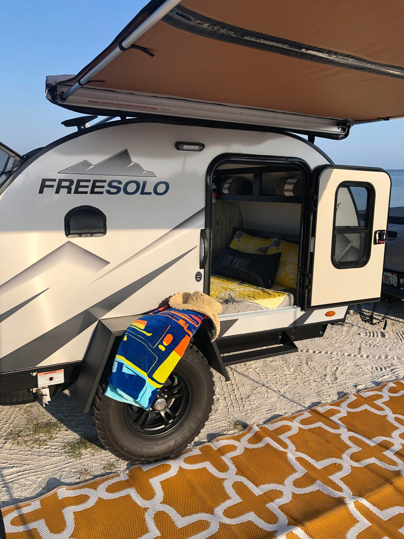 FREESOLO teardrop RV rental set up by the water, awning extended, door open to interior. Perfect for beach camping. — photo 7