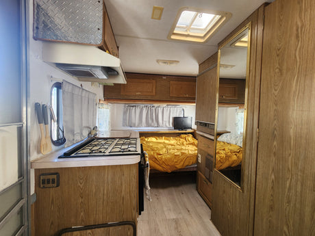 Step inside this comfortable RV rental! View of kitchen, bedroom, and living area, complete with wood accents and skylight.