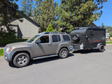 Grey Nissan Xterra SUV with a black InTech Flyer adventure camping trailer. Rent this RV for your next outdoor trip!