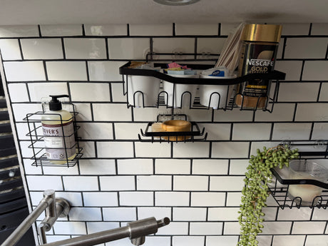RV rental kitchen: space-saving wall organizers hold dish soap, coffee, cups, and a plant against white subway tiles.