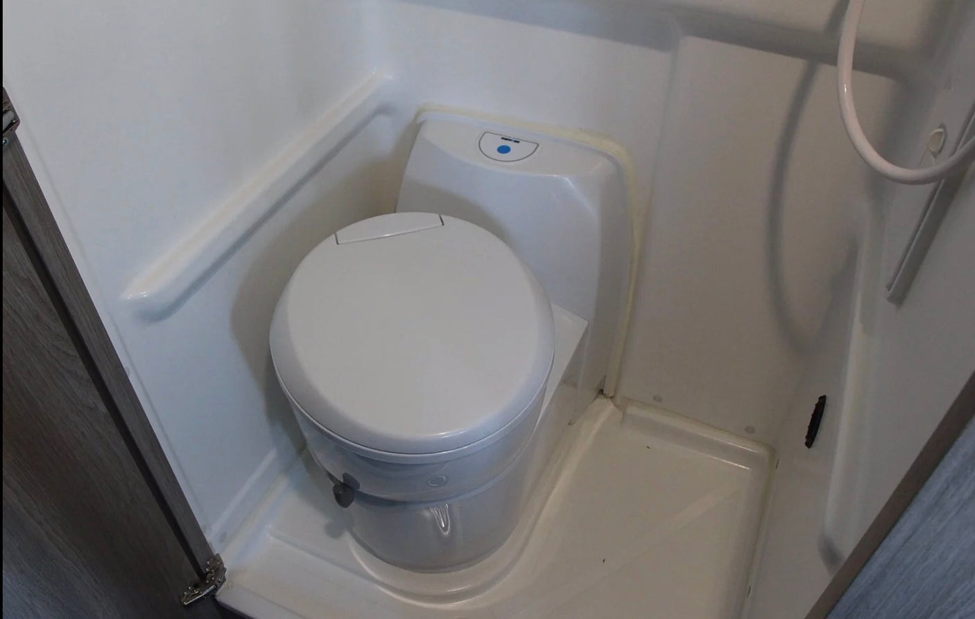 RV rental compact wet bath with white toilet and integrated shower area. Ideal for mobile living.