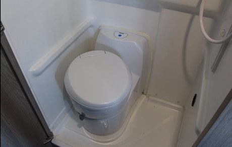 RV rental compact wet bath with white toilet and integrated shower area. Ideal for mobile living.