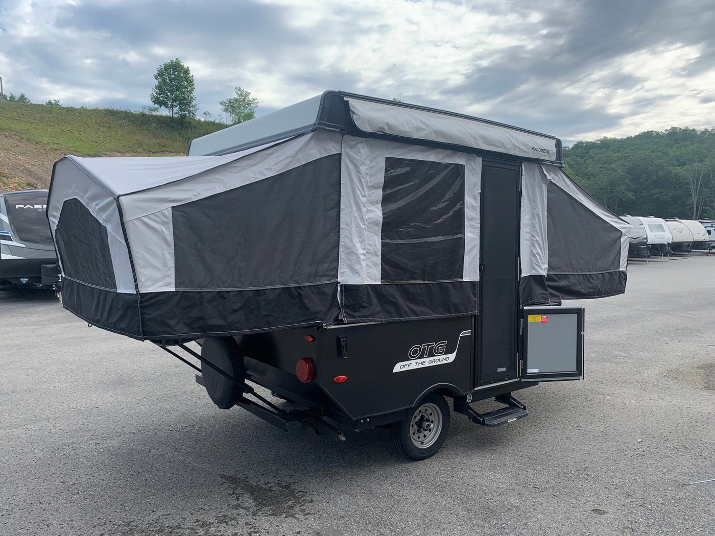 This black and white OTG pop-up camper is ready for RV rental, fully set up with extended fabric sides and Dometic awning. — photo 1