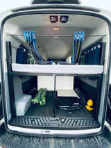 This is the rear interior of an RV rental camper van. It features a neatly made bunk bed, privacy curtains, and organized storage space below.