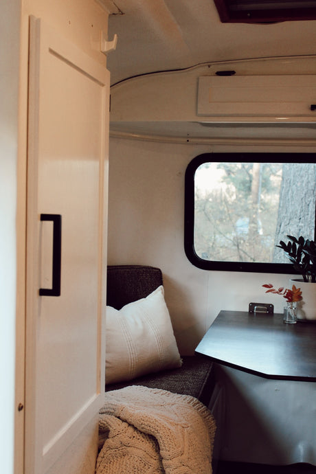  and comfortable seating with patterned blanket and pillows.|Cozy RV rental interior: dark wood table