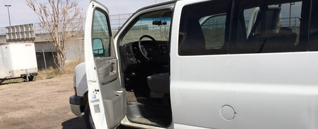 White Chevrolet Express-style van for RV rental has its driver's door open, showing the interior.